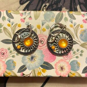 Silver sun and moon earrings with yellow gem in the center.